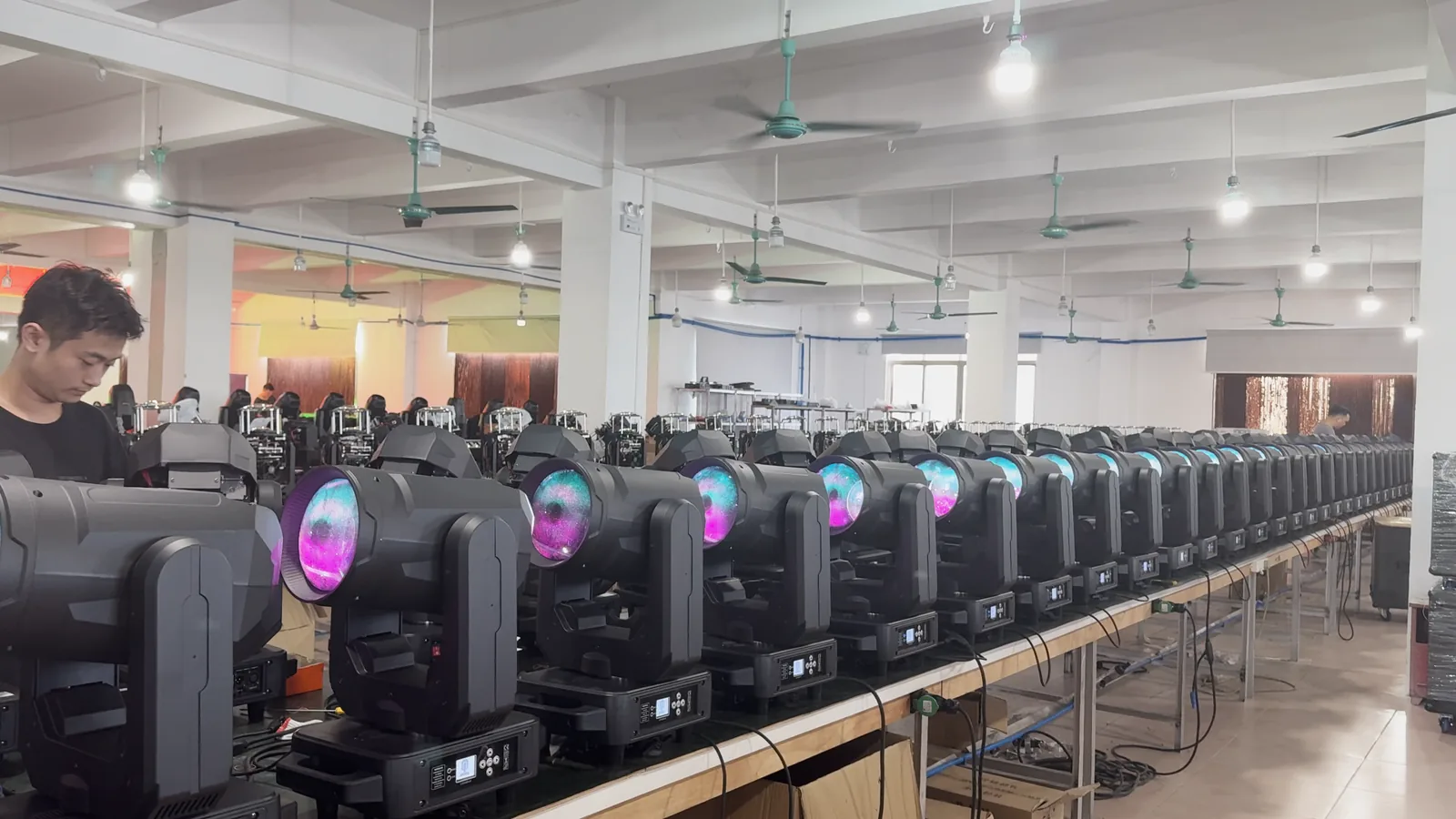 Beam moving head fixtures arranged across a workshop production line