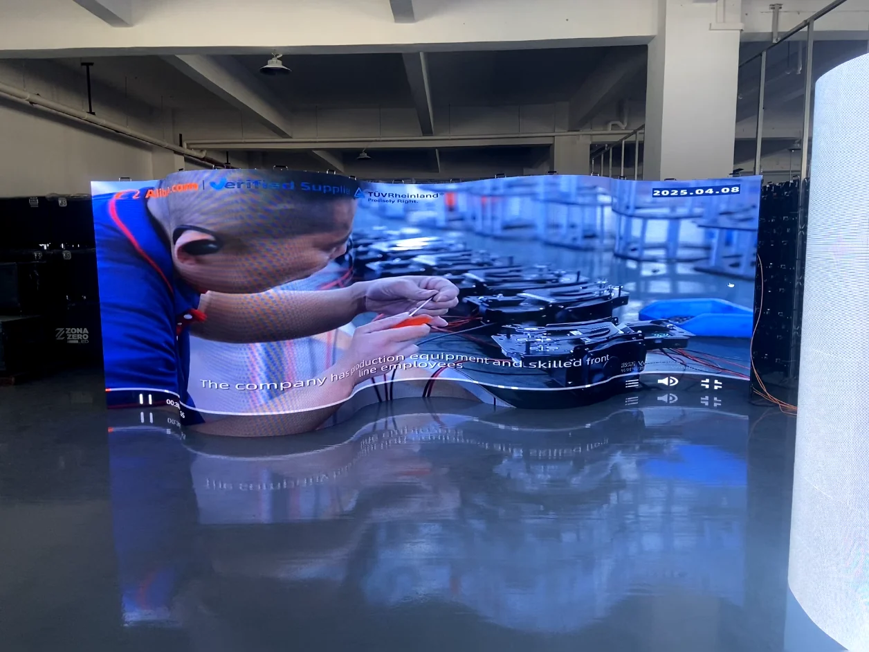Wide indoor LED display assembled in a wave curve and playing factory footage