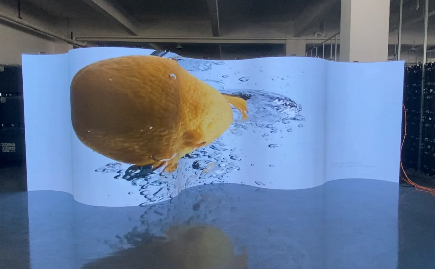 Wave-shaped indoor flexible LED screen showing an orange video in the workshop