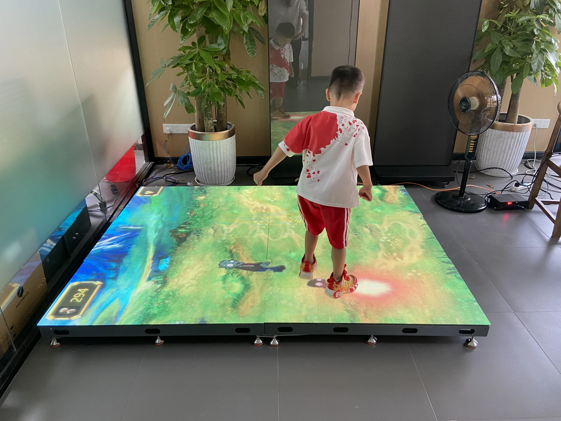 Child interacting with a modular LED floor screen showing responsive visual content