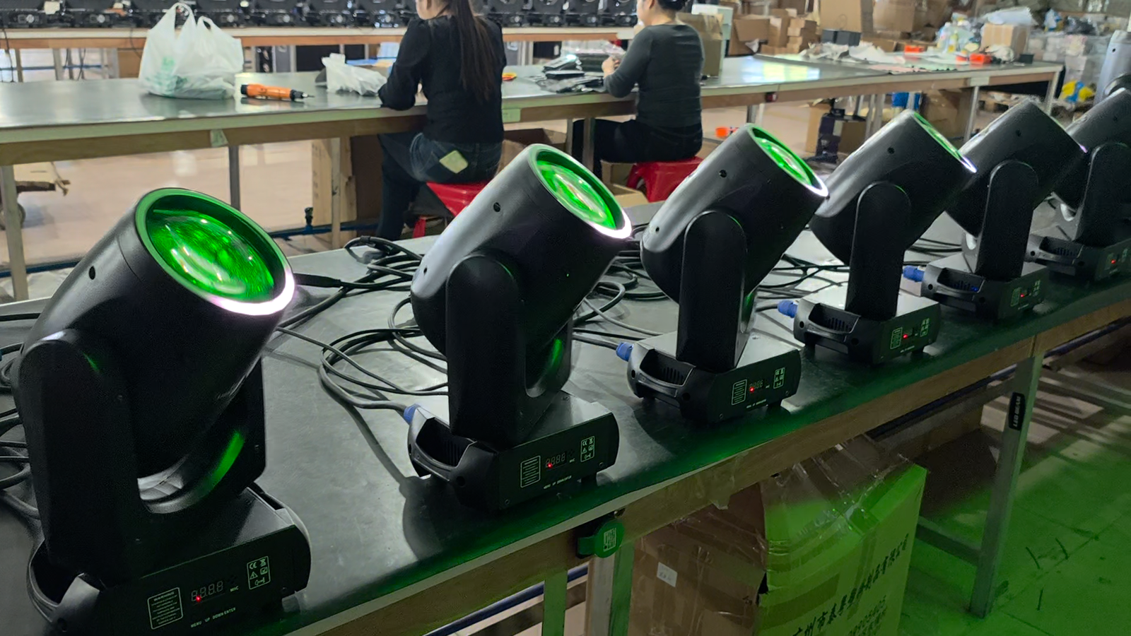 Beam moving heads tilted upward with green lenses at the workshop bench