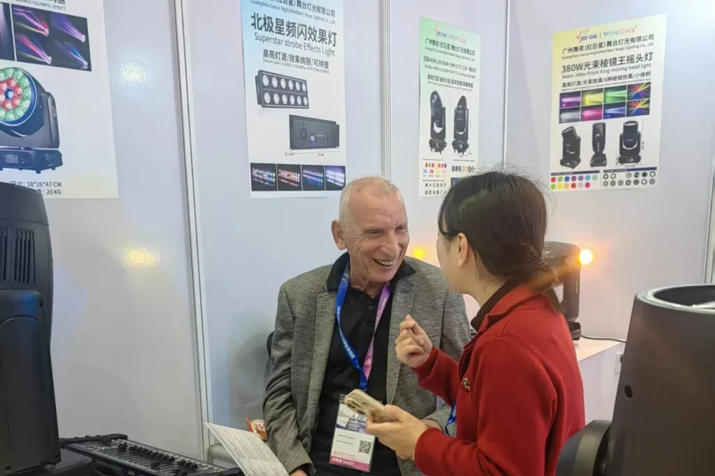WUYESTAGE representative speaking with an exhibition visitor beside stage lighting products in Shenzhen