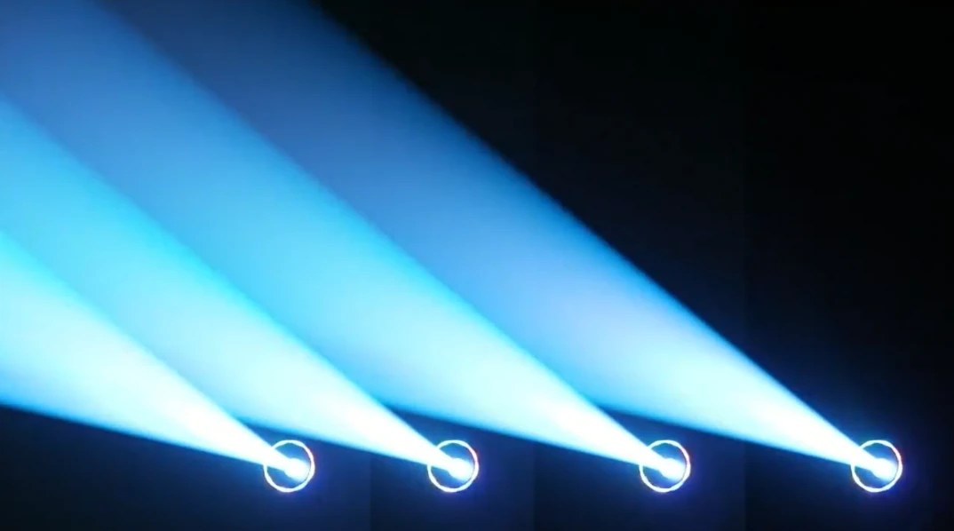 Four moving heads producing blue aerial light in a dark demonstration scene