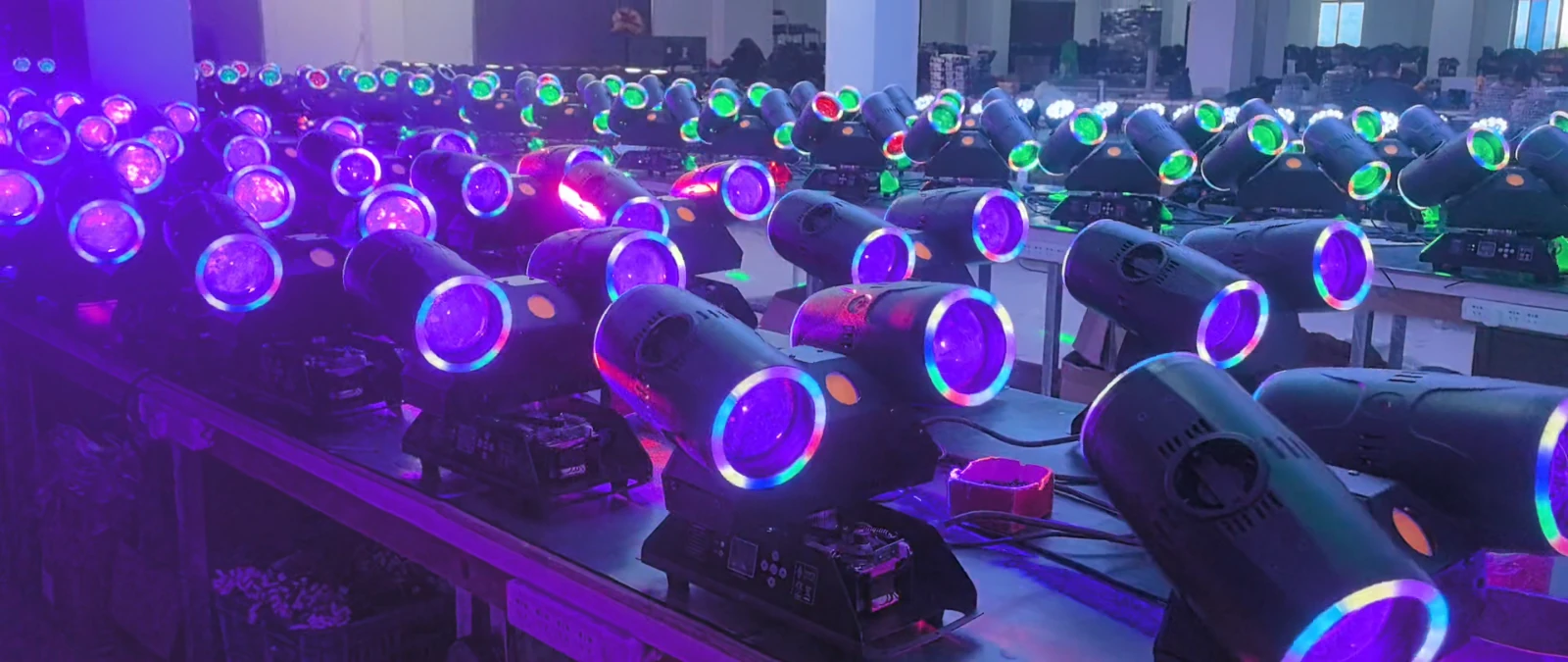 Rows of twin-head fixtures powered on with purple light and colorful lens rims at workshop benches