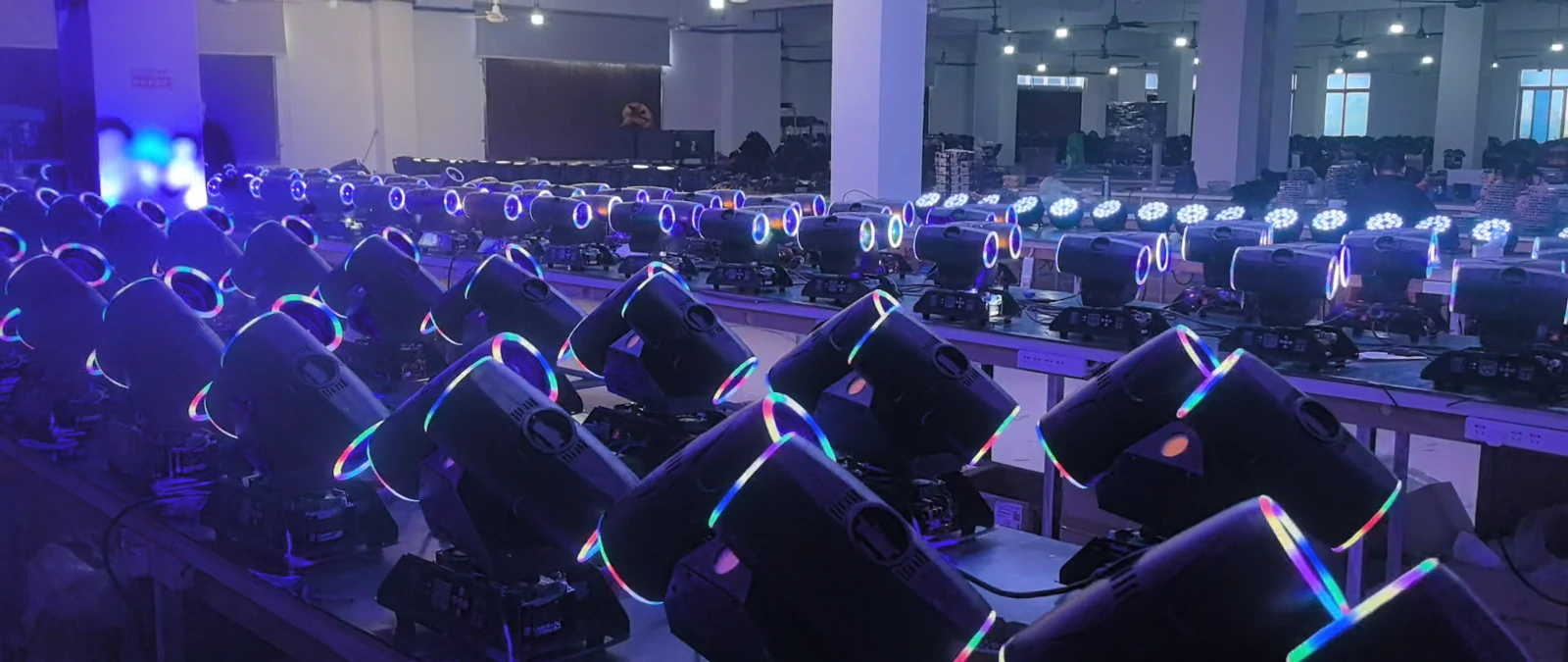Rows of powered-on twin-head fixtures showing illuminated lens rims at workshop benches